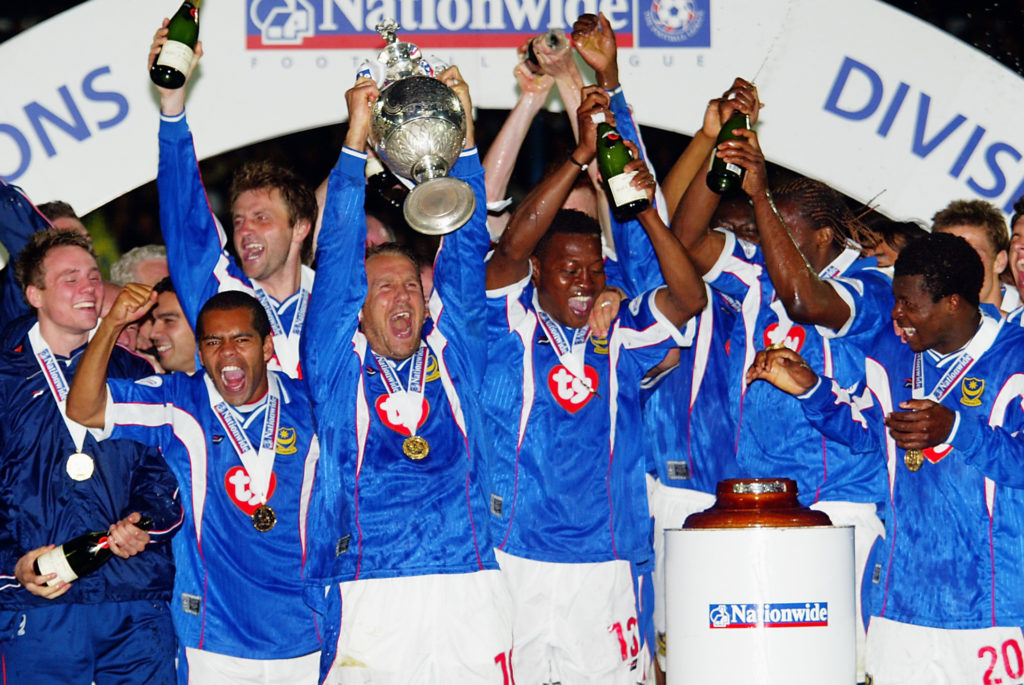 Paul Merson of Portsmouth lifts the trophy up as his team-mates celebrate